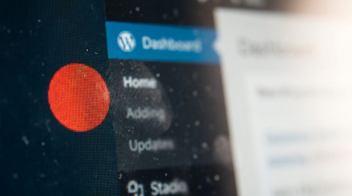 A laptop screen showing a WordPress admin dashboard with a red notification badge indicating multiple pending plugin updates