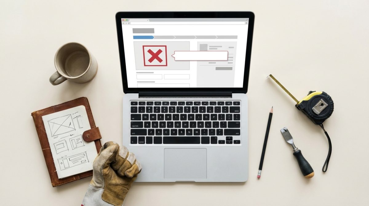 A small UK trades business owner looking frustrated at a laptop showing an online store checkout page with an error message