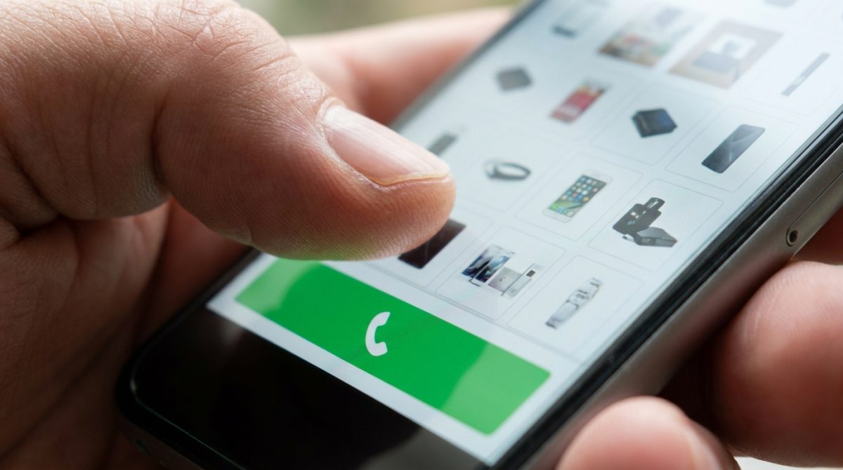 A person's hand holding a smartphone displaying a local business website with a prominent click-to-call button and fast-loading images