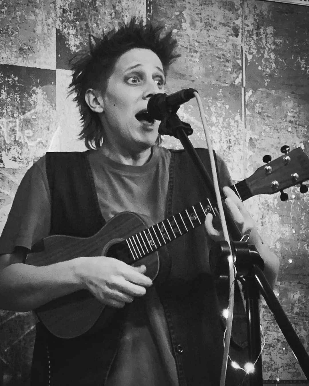 Fragile Lucy singing into a microphone with her ukulele