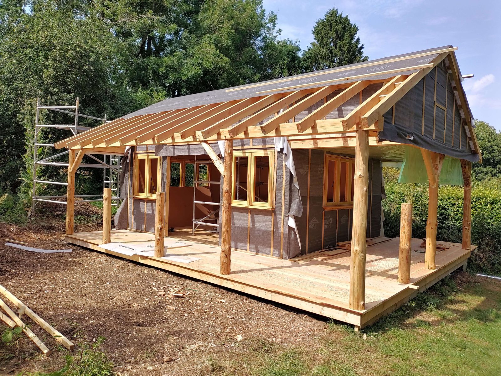 Greenwood cabin under construction with roundpole veranda posts